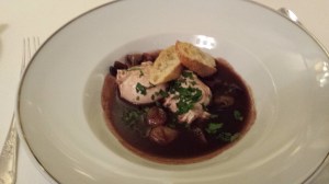 Poached egg a in a red wine sauce with onion and bacon